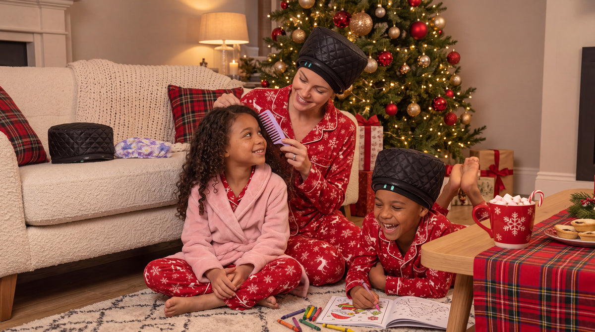 Mum combing her daughter's curls while her son colours in, all in Christmas pyjamas, wearing Team Texture Heat Hats